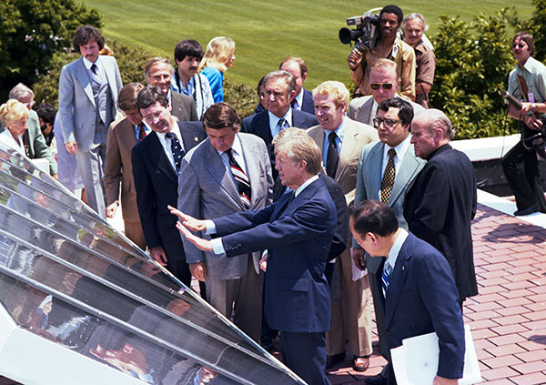 President Carter demonstrating solar panel features as a crowd looks on.