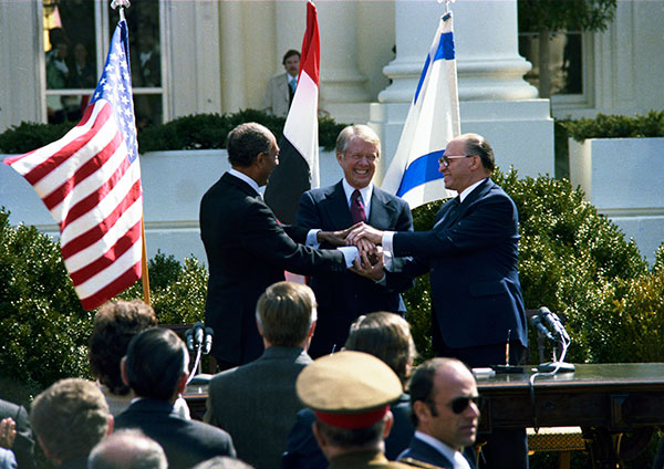 Anwar Sadat, President Carter, and Menachem Begin engage in a 3-way handshake. 