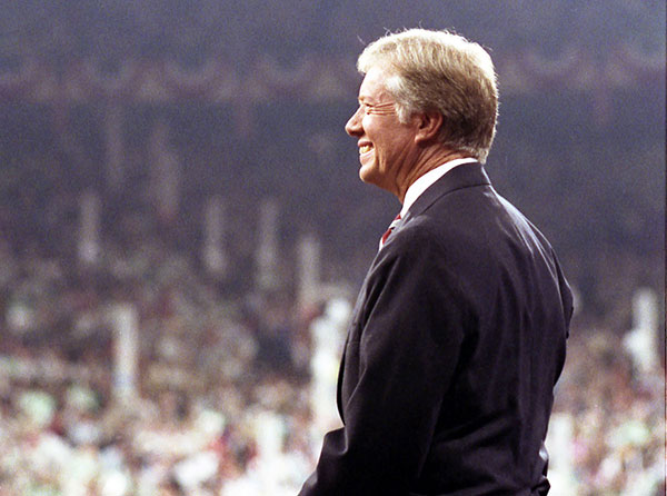 Jimmy Carter standing in profile in front of a large crowd.