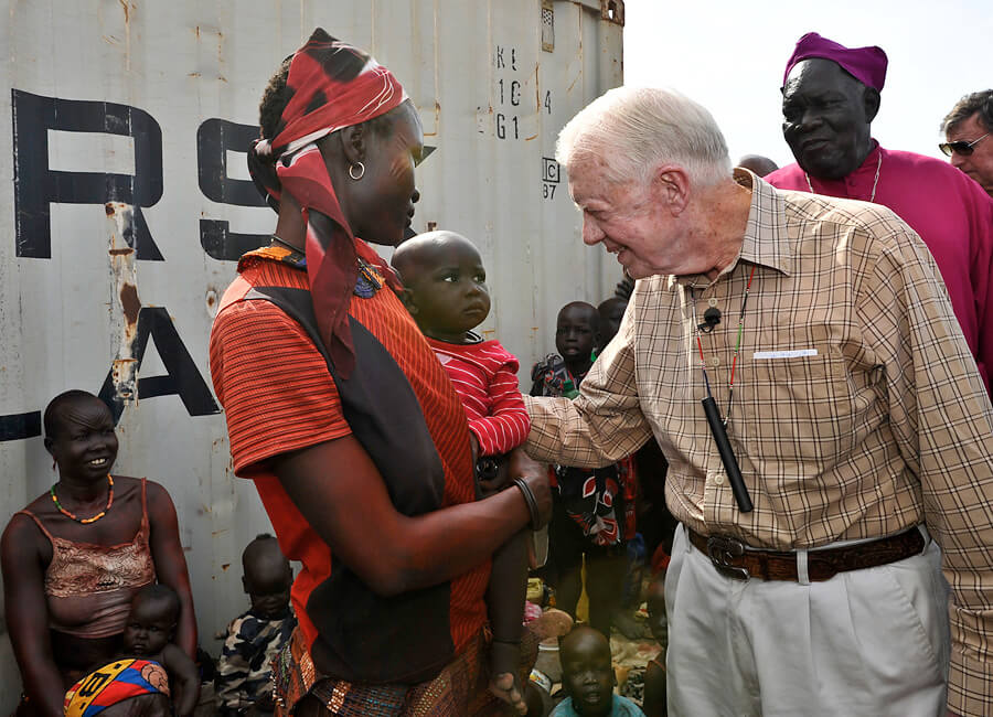 Jimmy Carter greeting a woman and child in a southern Sudan village.