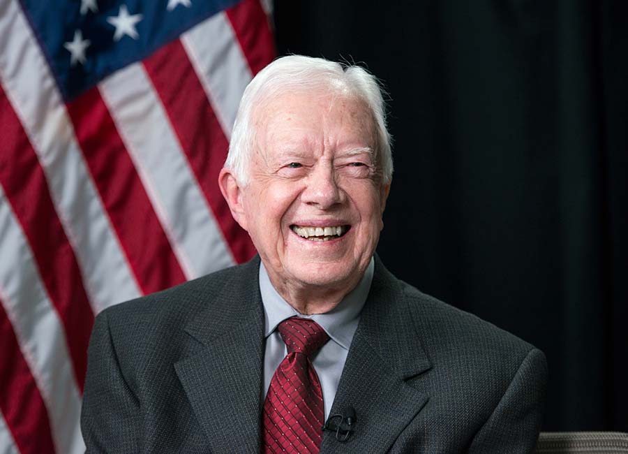 Jimmy Carter in front of an American flag backdrop.