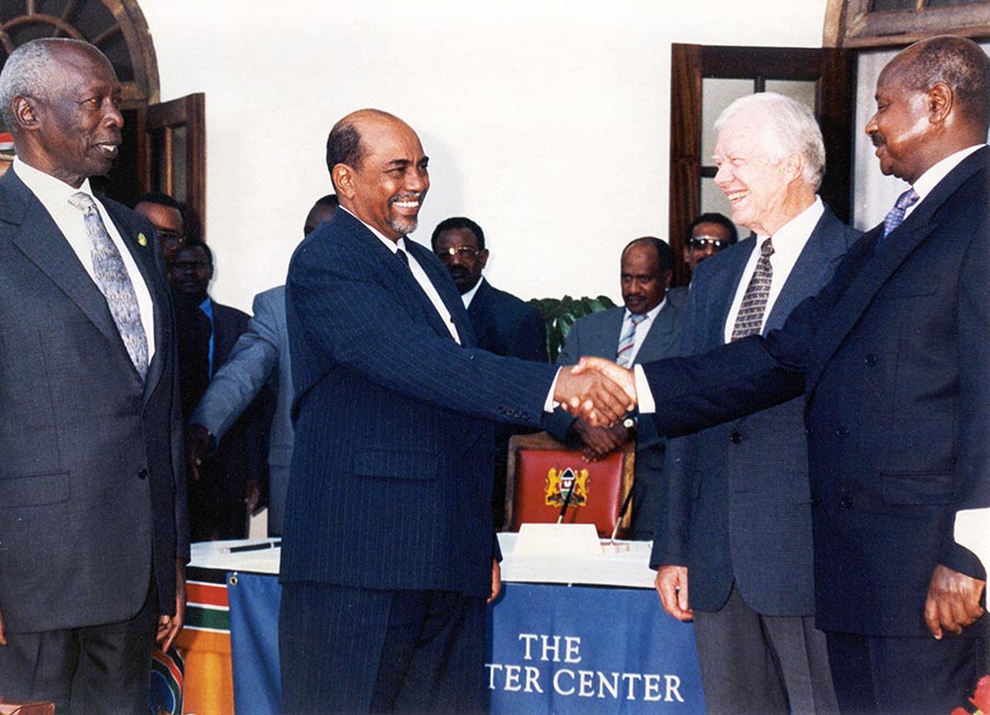 Jimmy Carter and Daniel arap Moi look on as Omar Al-Bashir and Yoweri Museveni shake hands.