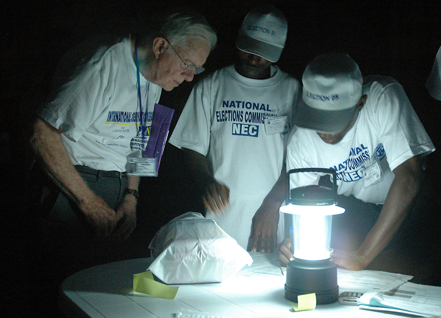 Jimmy Carter observing ballot counting by lamplight  in Liberia.