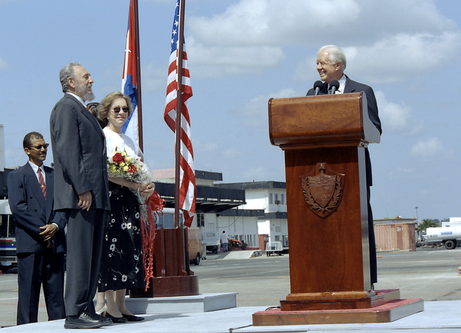 Jimmy Carter at a podium in Cuba with Fidel Castro and Rosalynn Carter.