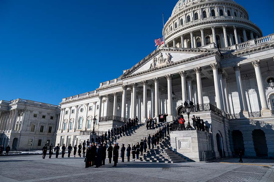 The U.S. flag flies at half-staff as military personnel line the steps of the Capitol while President Carter’s body is carried outside.