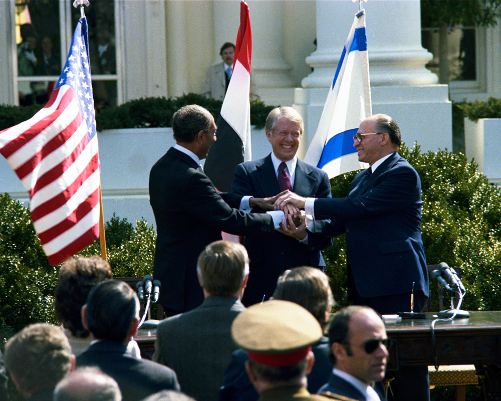 Anwar Sadat, President Carter, and Menachem Begin join in a 3-way handshake.