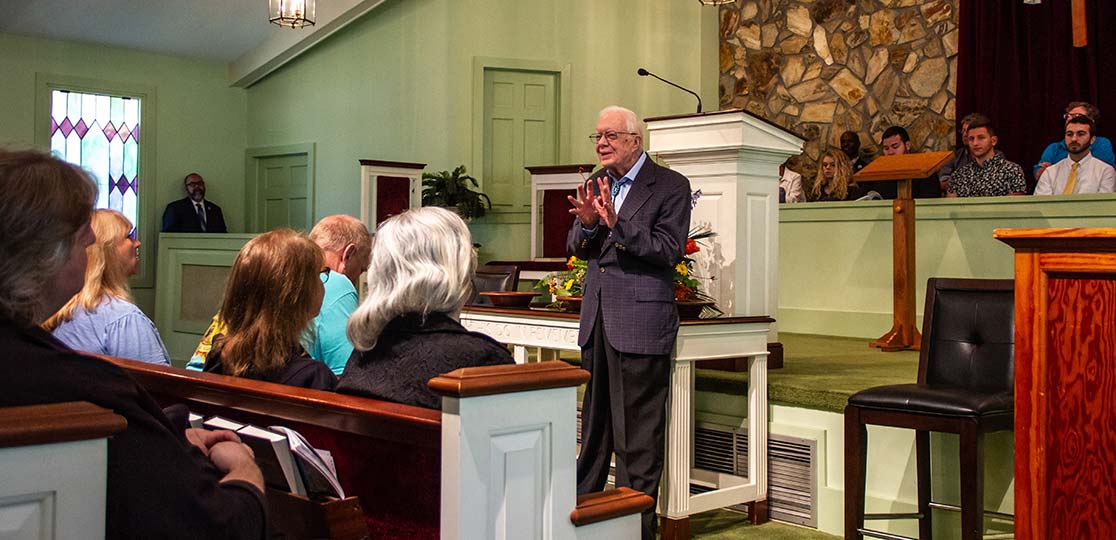 Jimmy Carter stands in front of a church congregation